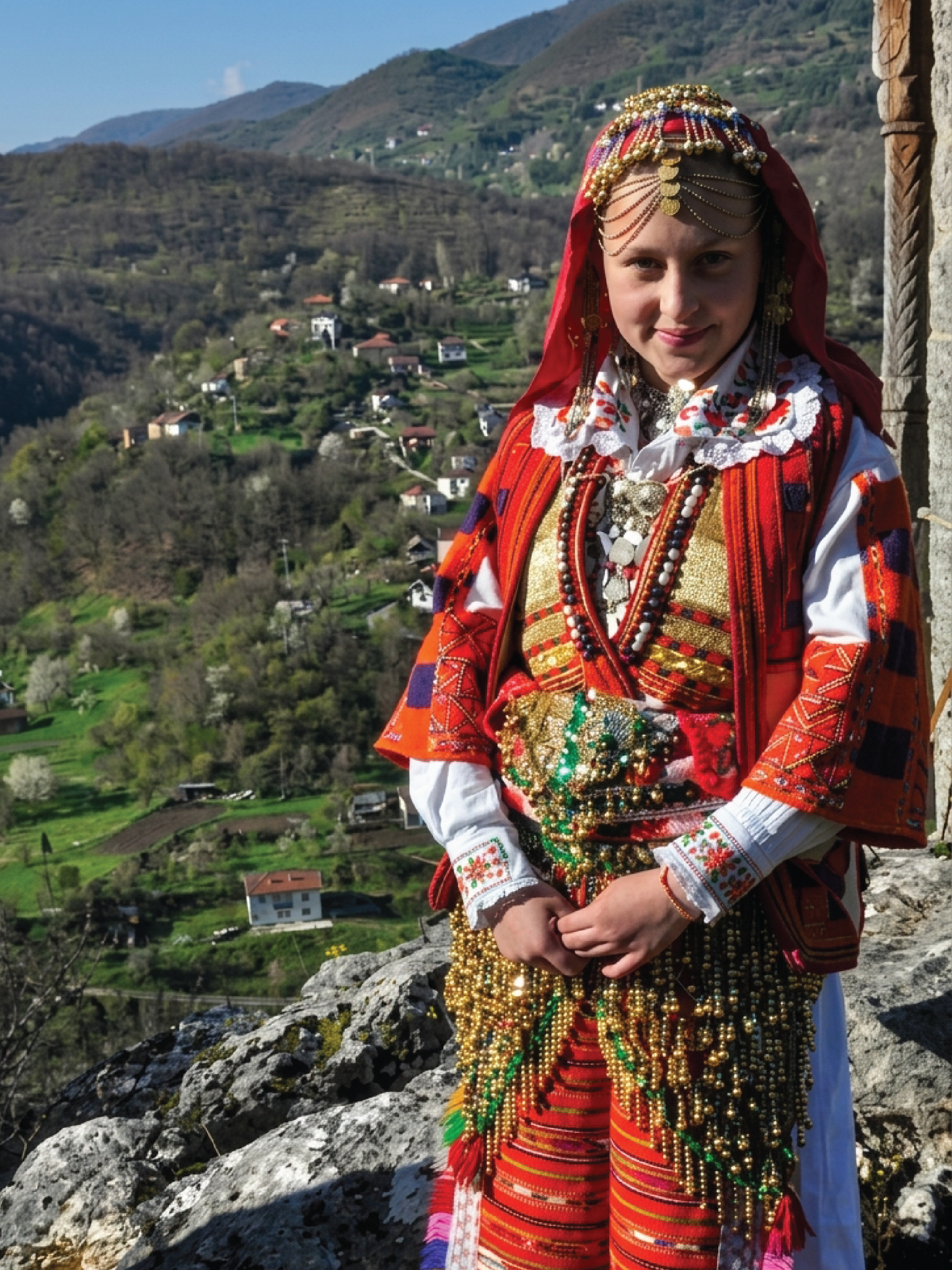 Young woman in richly ornamented traditional dress in a mountain village