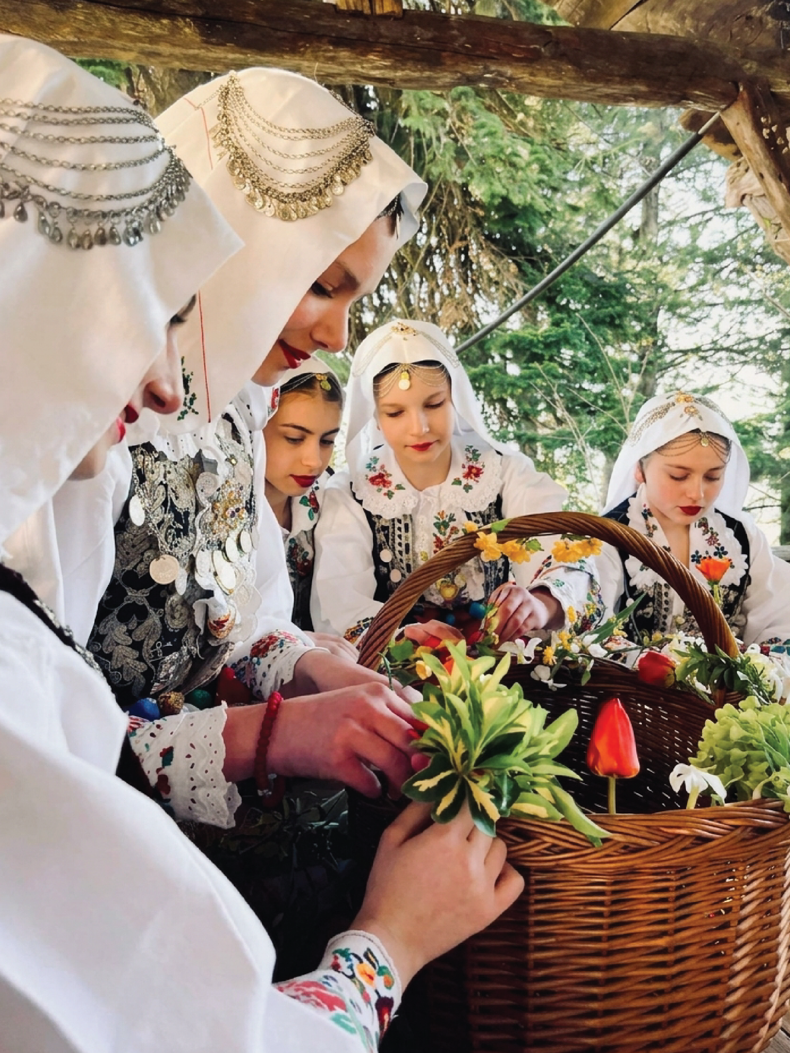 Young women in traditional dress arranging flowers in a basket