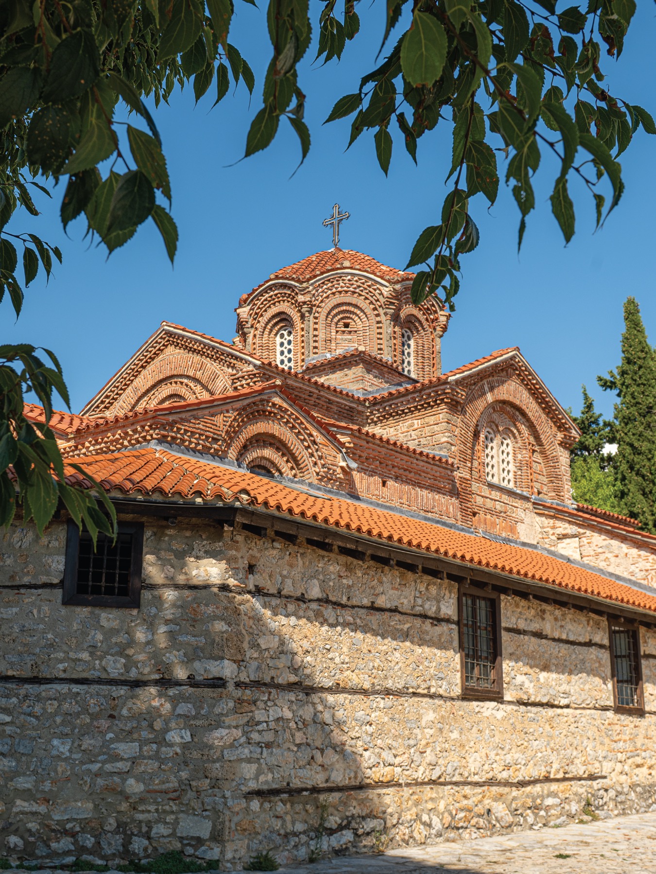 Church of the Virgin Mary Peribleptos in Ohrid framed by leaves against a blue sky.